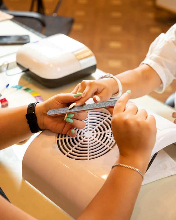 Close-up of a beautician giving a manicure with focus on nail care techniques.