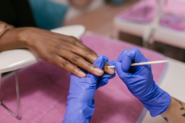 Close-up of a manicure session with blue latex gloves in a salon setting.