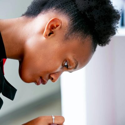 Close-up of a nail technician carefully applying polish to a client's nails in a salon setting.