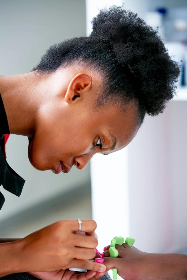 Close-up of a nail technician carefully applying polish to a client's nails in a salon setting.