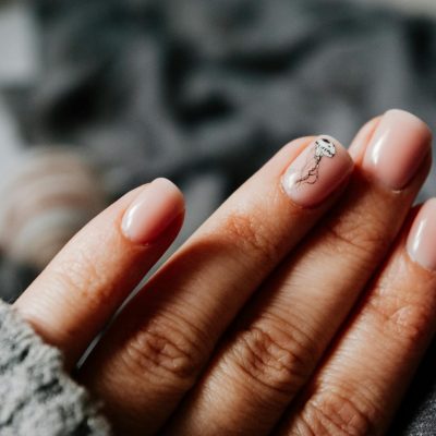 Close-up of a woman's elegant manicure featuring a jellyfish design on soft pastel nails.