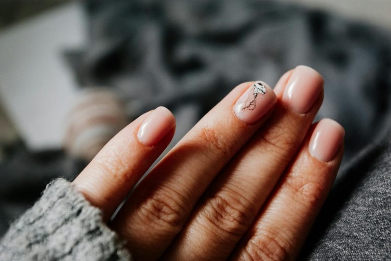 Close-up of a woman's elegant manicure featuring a jellyfish design on soft pastel nails.