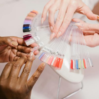 Close-up of hands choosing from a vibrant nail polish sample palette in a salon setting.